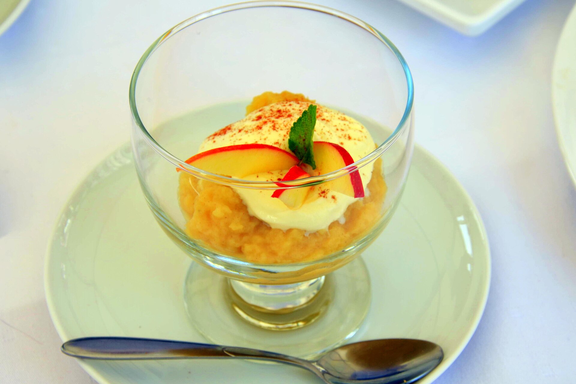 Puré de manzana en copa de vidrio, claro y con trocitos, con crema y rebanadas de manzana
