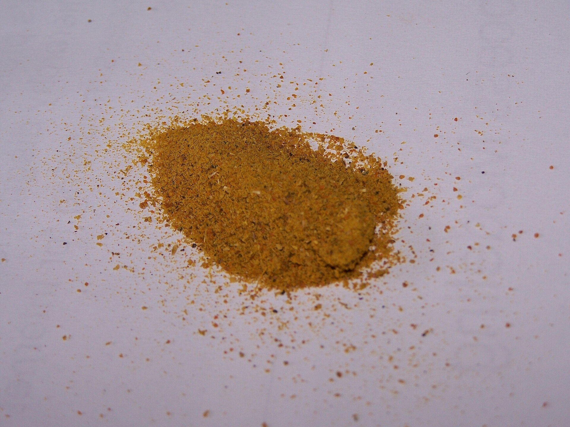 Montoncito de curry en polvo amarillo dorado sobre papel claro, molido fino