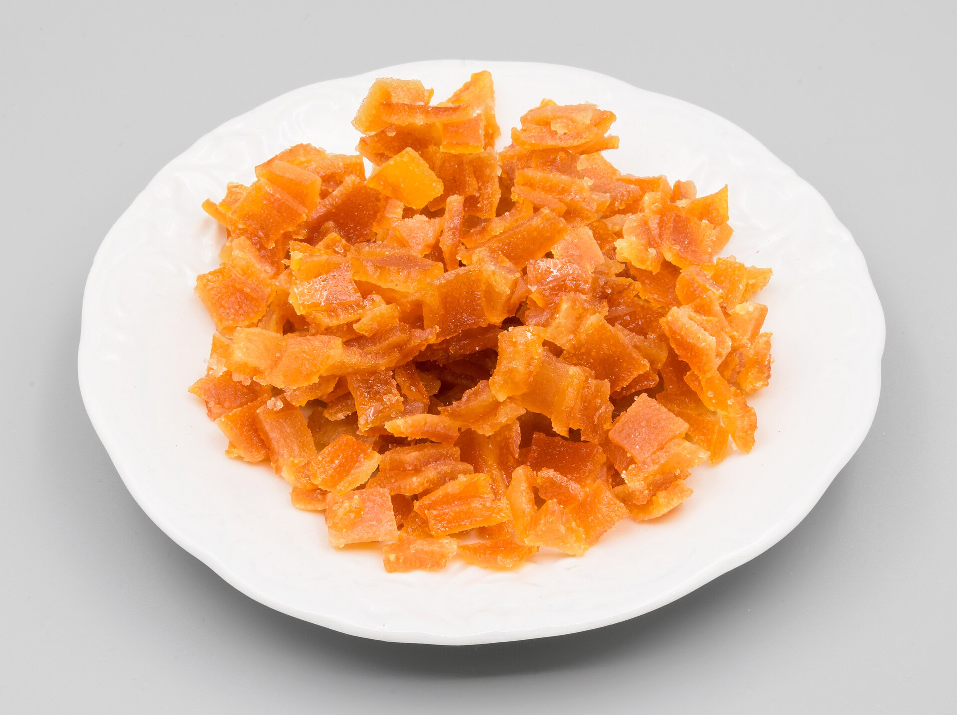 Plato con cáscara de naranja confitada en cubos, naranja y brillante