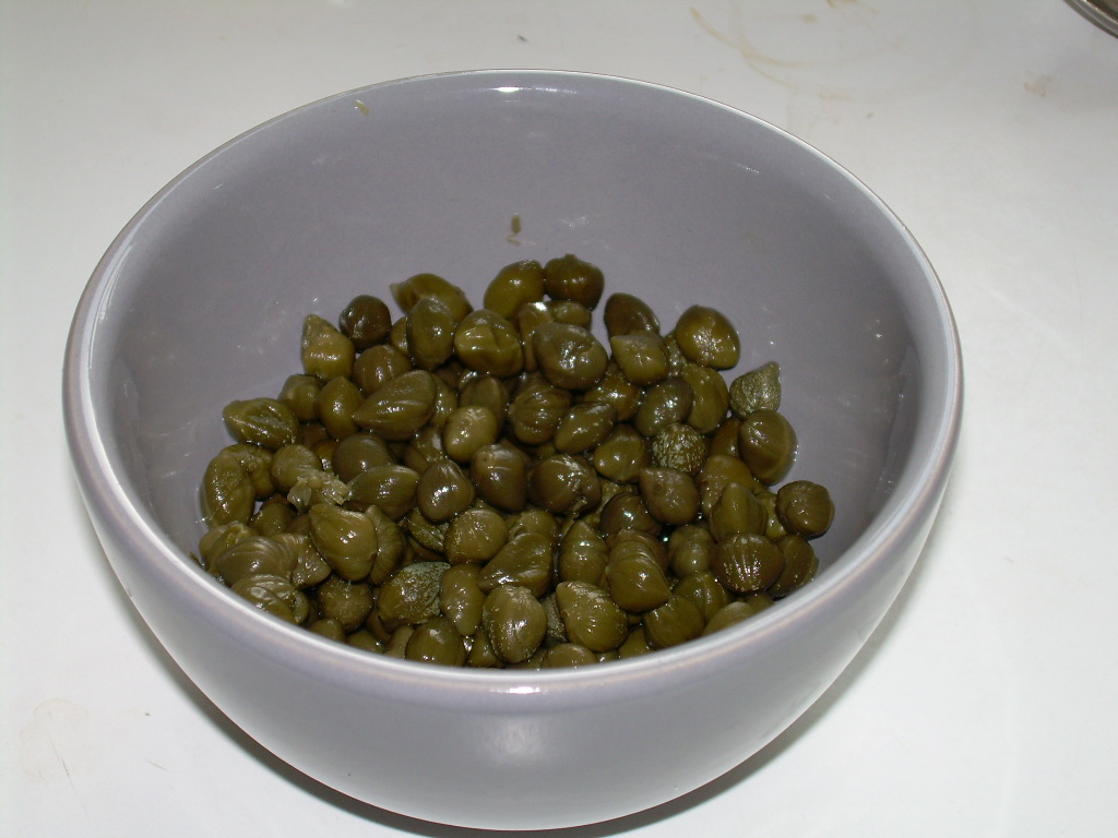 Alcaparras en salmuera en un tazón gris, verde olivo y brillantes