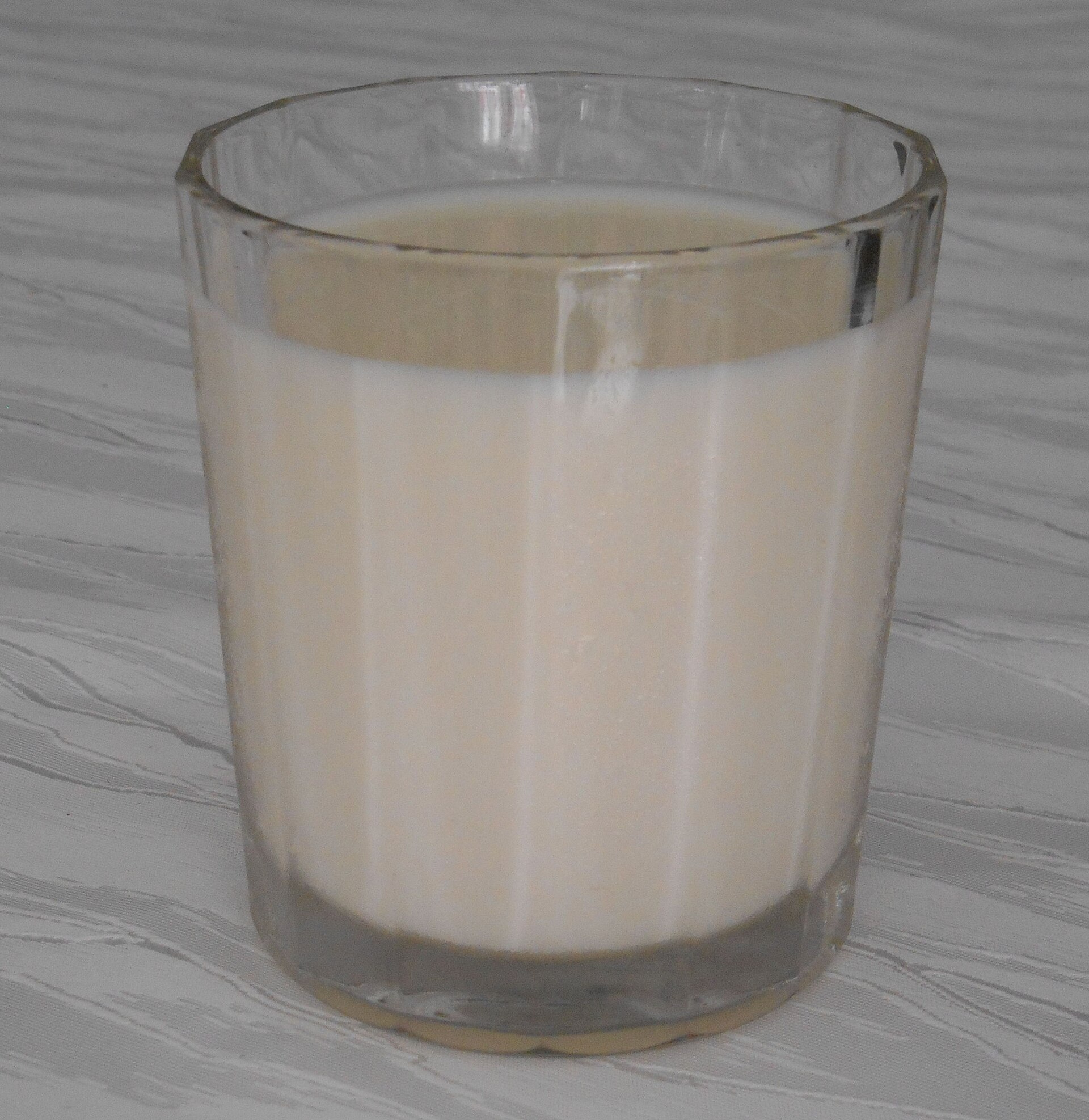 Un vaso de leche entera visto de lado, blanca y opaca